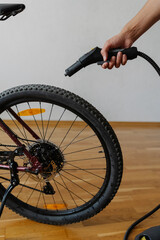 Vertical cropped shot of cyclist male using steam cleaner to remove dirt and grime from tire of bicycle wheel at home, ensuring cleanliness, close-up. Concept of bike maintenance and service.