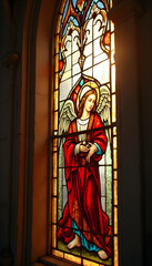 Fototapeta premium Ornate stained glass angels glow with sunlight in historic church window 