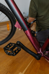 Vertical cropped shot of mechanic cleaning and polishing mountain bike frame with cloth, emphasizing maintenance and repair skills in workshop environment, close-up. Concept of bicycle service