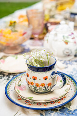 Hand painted floral teacup with baby’s breath on stacked plates at tea table