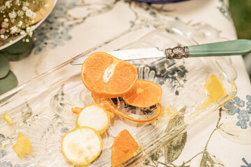 Sliced orange and lemon on glass tray with vintage knife and floral tablecloth