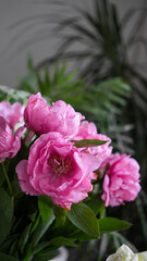 bouquet of pink peonies and green leaves in a vase close-up