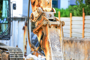 Detailed view of an excavator’s arm with a hydraulic hammer attachment. The worn metal, bolts, and hoses reveal heavy use in demolition or construction on an active urban job site