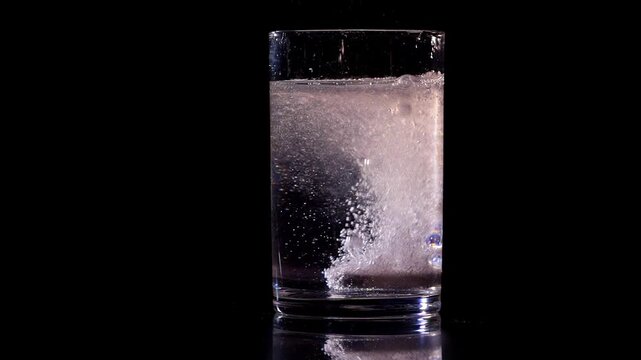 Electrolyte effervescent tablet. A glass of water with an effervescent tablet on a black background. Health and diet for warm, hot days and for athletes. Dehydration and hydration.