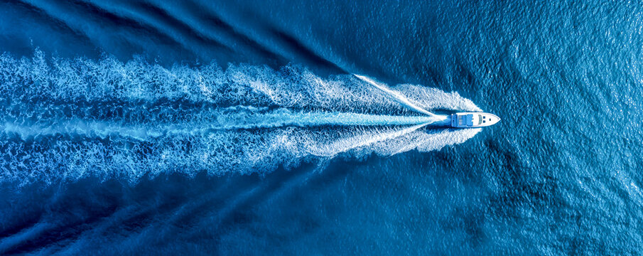 Top-Down View of Boat Trail on Deep Blue Ocean Surface with Smooth Ripples and White Foam