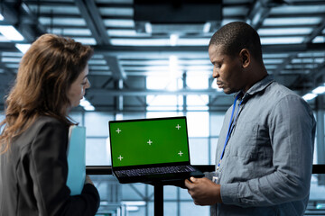 Engineer in data center using green screen laptop, refining server virtualization strategies,...