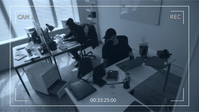 Security camera footage of two masked male criminals hacking into corporate computers then passing folder with documents searching for confidential database of clients during industrial espionage