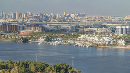 Fototapeta premium Aerial view of blue canal near green park Dubai city, United Arab Emirates Timelapse