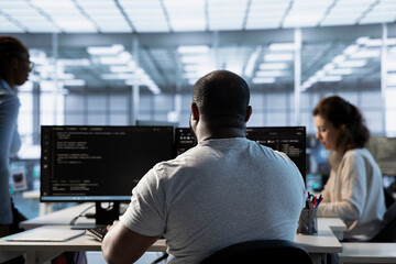 Admin in server hub next to colleagues tasked with protecting data against hacking attacks. African...