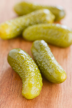 Sour fermented pickled cucumber, pickle or gherkin on wooden board (Selective Focus, Focus one third into the image)