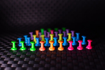 Colored pins placed on a black background.
