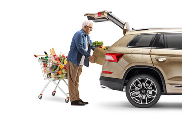 Mature man with a shopping cart loading groceries in a trunk