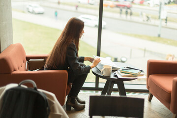 A woman is peacefully sitting at a table while gazing out of a window, reflecting on her thoughts...
