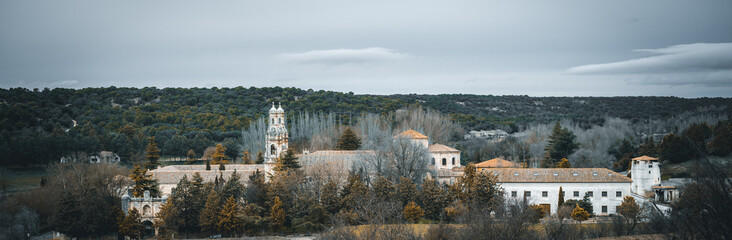 Historic Monasterio de la Santa Espina surrounded by lush trees and hills under a moody sky, capturing the region’s heritage. Scenic view in Castilla y León, Castile and Leon