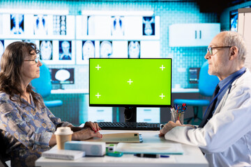 Old patient and specialist at check up visit next to chroma key display, discuss about prescription...