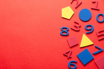 Colorful foam numbers and geometric shapes on red background and copy space. Back to school concept. 