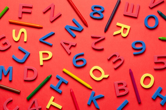 Colorful foam letters, numbers and crayons on red background. Back to school concept. - Powered by Adobe
