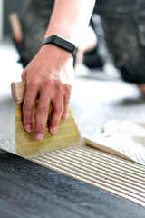 Handwerker trägt Kleber mit Zahnspachtel auf