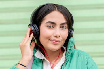 Young latin woman listening to music with headphones and enjoying the moment in the city