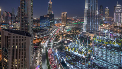 Fototapeta premium Panoramic skyline view of Dubai downtown after sunset with mall, fountains and skyscrapers aerial day to night timelapse