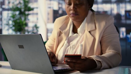 Female general manager does online shopping paying for clothes on website, buying things and...