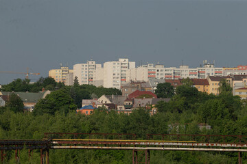 This is a vibrant cityscape featuring numerous tall buildings amidst a lush arrangement of trees...
