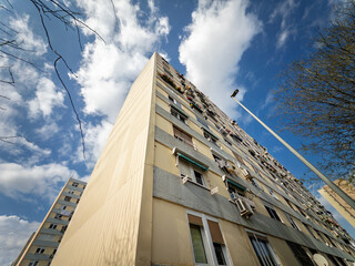 Low angle view of a concrete apartment block in Bellvitge, Barcelona suburb, with balconies, laundry and air conditioners, illustrating Spanish social housing and urban poverty beneath patchy clouds.