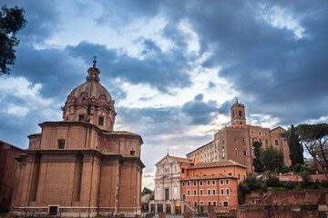 Soft sunset light strikes the domed church of Santi Luca e Martina and neighbouring palazzi at the edge of Rome Foro Romano, roman forum, Italy, as dramatic evening clouds roll across the sky.