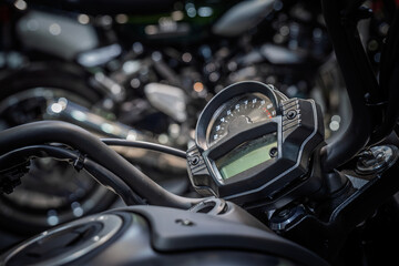 Close up of a motorcycle tachometer showing the rpm scale and redline, photographed under showroom lights with shallow depth of field, on precision engineering and glossy black instrument housing.
