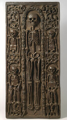 Medieval stone carving depicting skeleton surrounded by infant skeletons; religious art; museum display; historical artifact