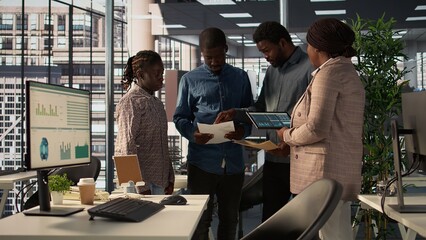 Professional team analyzing archived data on a financial file during meeting, collaborating on...
