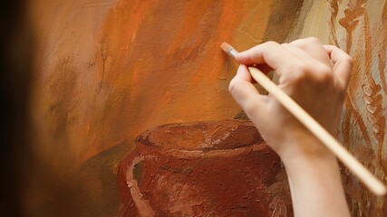 Female painter working on a canvas to create an artwork in studio, using bristles to apply dye with precision. Presenting her skill to create unique painting for the art gallery. Camera A.