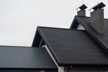 Distinctive black roofing with angular shapes showcases modern architecture against an overcast...