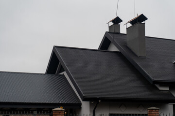 A contemporary building showcases a stylish sloped roof with two chimneys. The design blends modern...