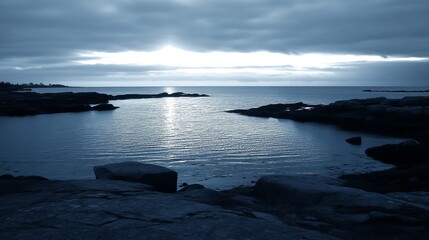 Moody coastal scene, tranquil water,  dark rocks