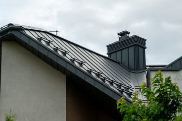 The photograph showcases a stylish roof of a modern home featuring sleek lines and a unique chimney...