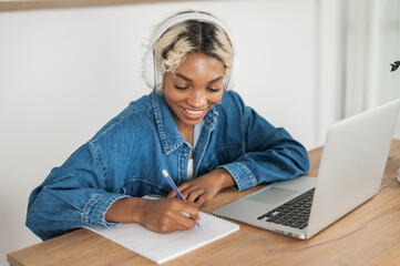 young happy african american student girl at the desk writing lecture,doing homework,take notes,learning etc