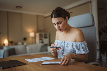 Adult woman have contactless payment scan invoice on cellphone at home
