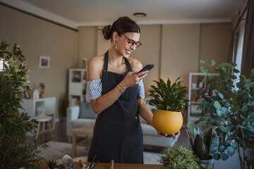 Woman use her mobile phone to take pictures of her plants indoors.