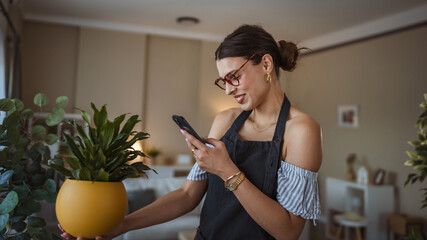 Woman use her mobile phone to take pictures of her plants indoors.