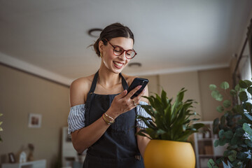 Woman use her mobile phone to take pictures of her plants indoors.