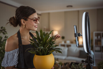 woman gardener blogger show her potted plants recording video at home