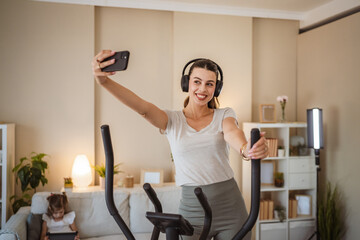 woman with headphones take a self portrait on stationary bike at home