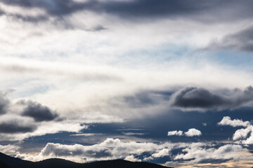 contrasty sky with dark and white clouds over tasmanian mountains in Australia