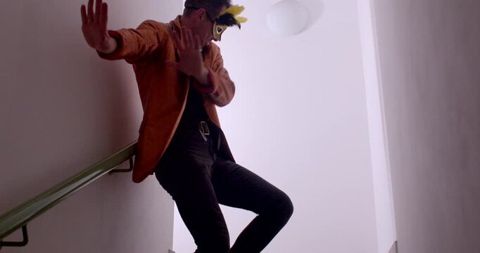 A man performs funny antics on a staircase, including squatting, tossing a ball, and balancing a banana on his head, before dancing