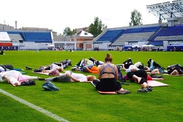 Russia, June 20, 2024:Group of people participating in a yoga session on a sports field, standing in a circle, showcasing concentration and unity