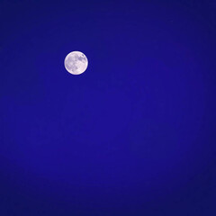 Full moon shining brightly in a deep blue night sky