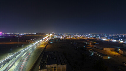 Traffic on a big road junction in Ajman aerial view from rooftop at night timelapse.