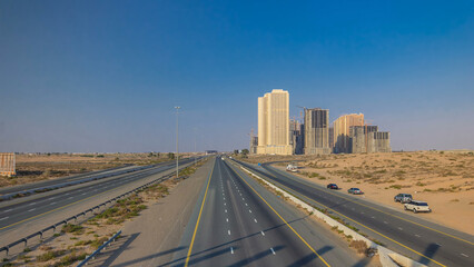 Highway roads with traffic timelapse in a big city from Ajman to Dubai before sunset. Transportation concept.