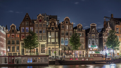 Panoramic timelapse of the illuminated famous Dancing Houses along the Amstel River at night. Amsterdam, Netherlands